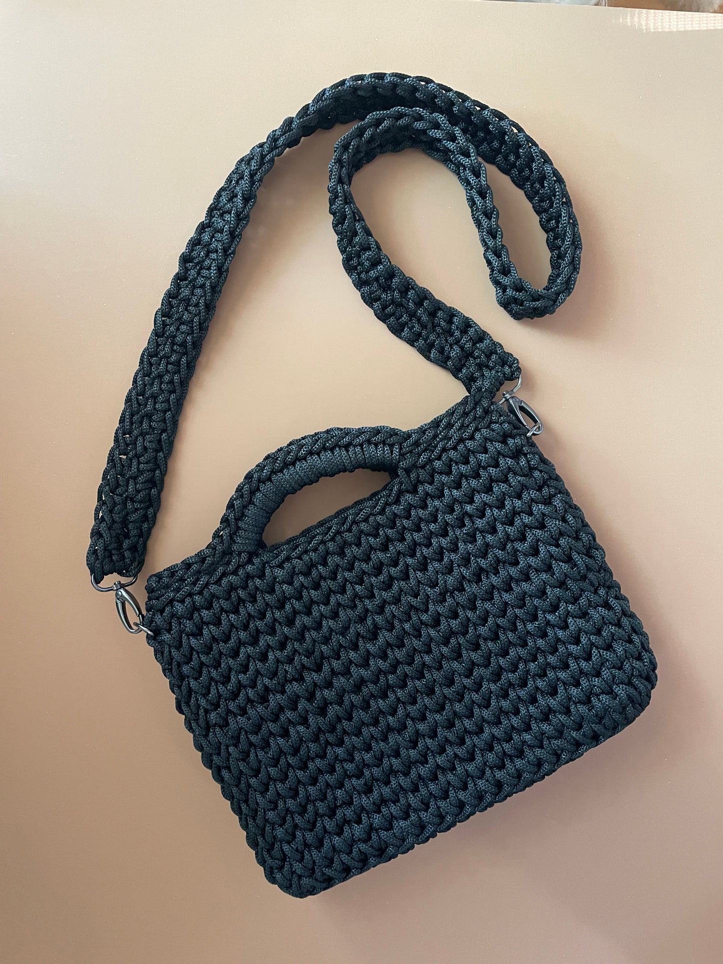 Dark blue woven handbag with a strap on a beige background